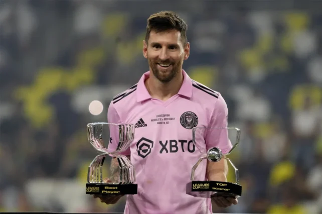 messi holding 2 trophies